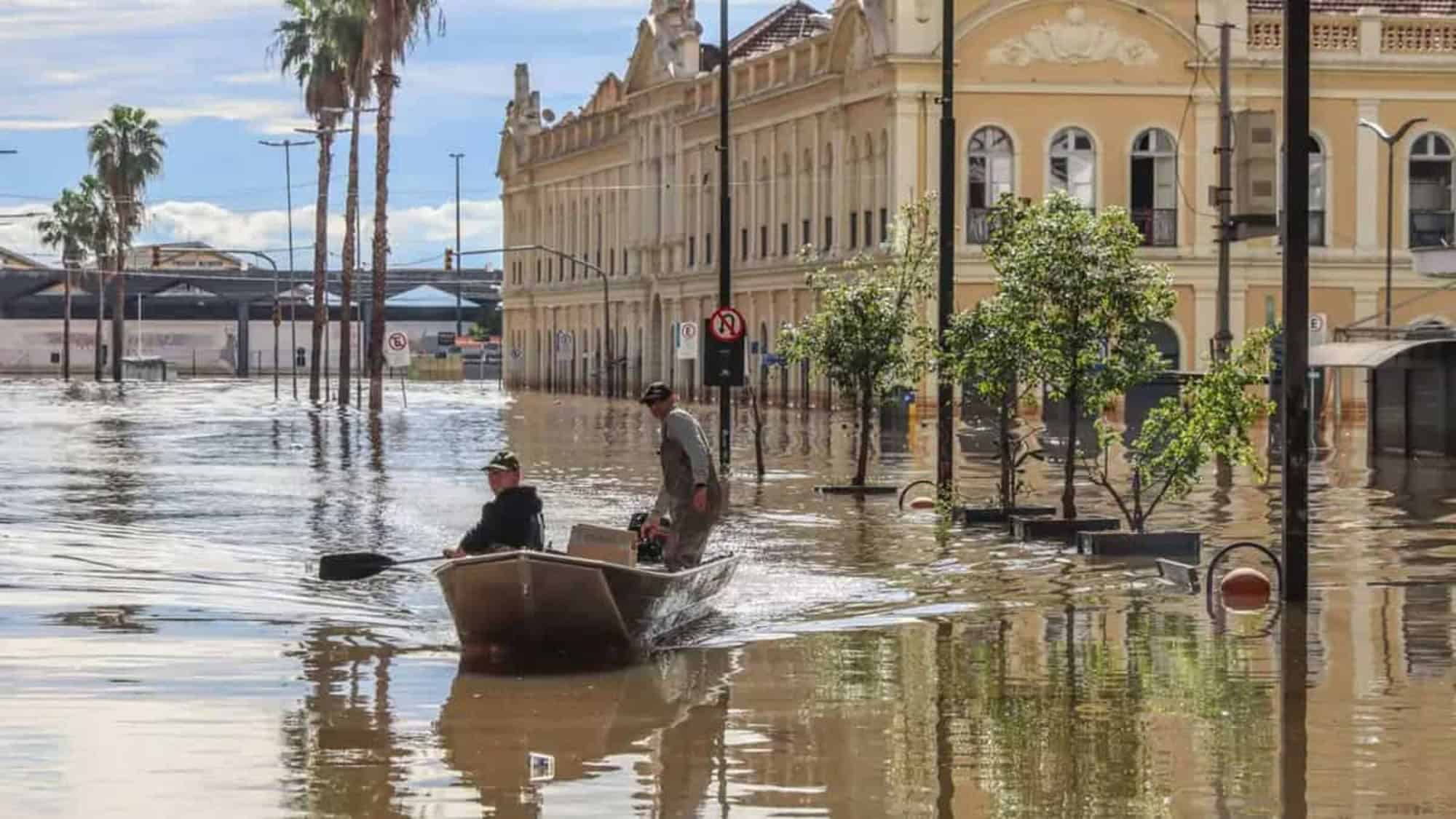 Homens andando de barco em enchente no Rio Grande do Sul